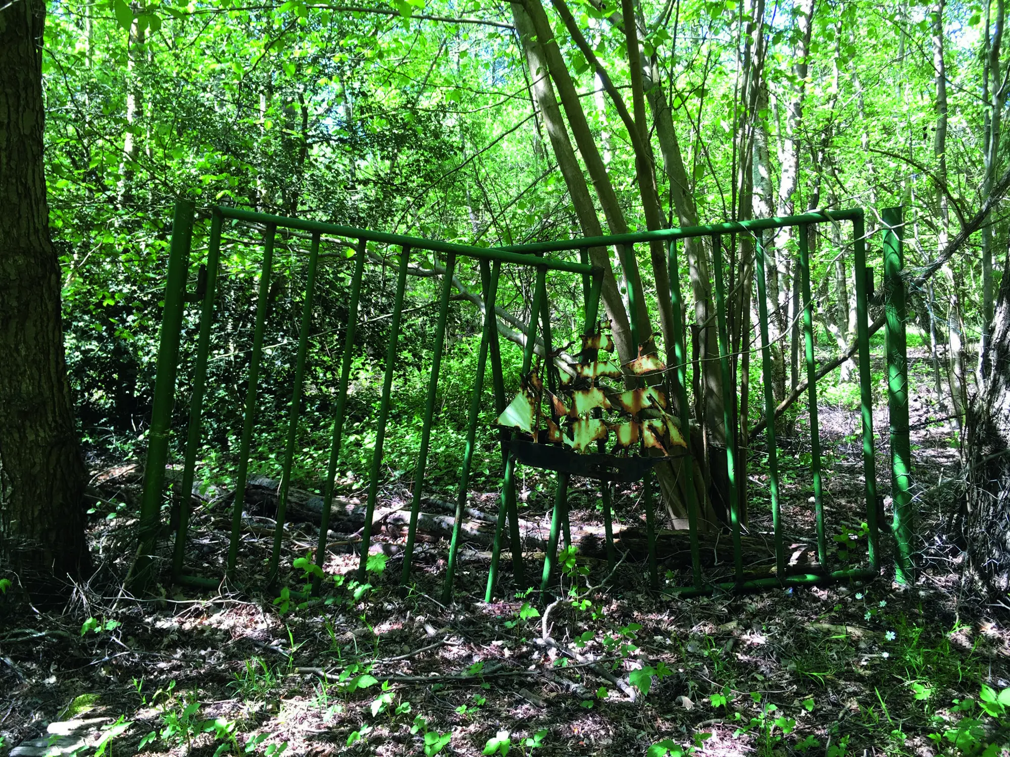 Altes Eisentor mit einer Segelschiffdekoration im Grünen