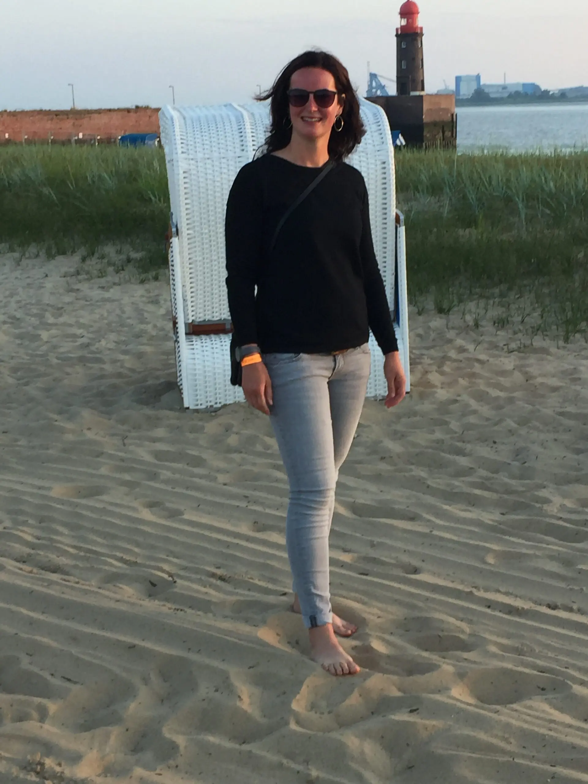 A7BA0C7C-E69F-42FA-A49A-2AE257F95D91 Lisa Keller spaziert barfuß im Sand des Weserstrands vor einem weißen Strandkorb
