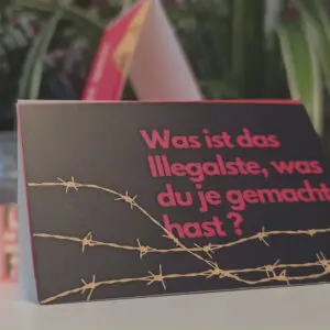Nahaufnahme einer Karte mit einer Stacheldraht-Grafik und dem Text "Was ist das Illegalste, was du je gemacht hast?"