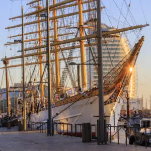 Schulschiff Deutschland an der Kaje, im Hintergrund spiegelt sich die Sonne im Atlantic Hotel Sail City