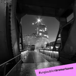 Schwarz-Weiß-Aufnahme vom erleuchteten Klimahaus Bremerhaven und dem Atlantic Hotel Sail City