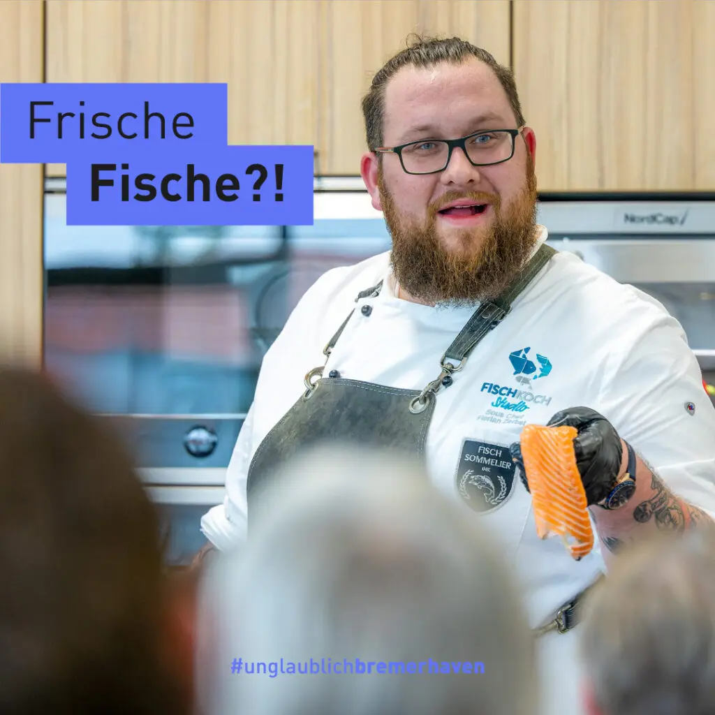 Ein Koch im Seefischkochstudio erzählt dem Publikum etwas über Lachs und zeigt dessen Filet.
