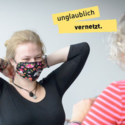 Lächelnde Frau setzt einen selbst genähten Mund-Nasen-Schutz auf, Text "unglaublich vernetzt"