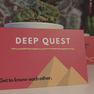 Nahaufnahme einer Karte mit zwei Pyramiden als Grafik und der Aufschrift "Deep Quest - Get to know each other".